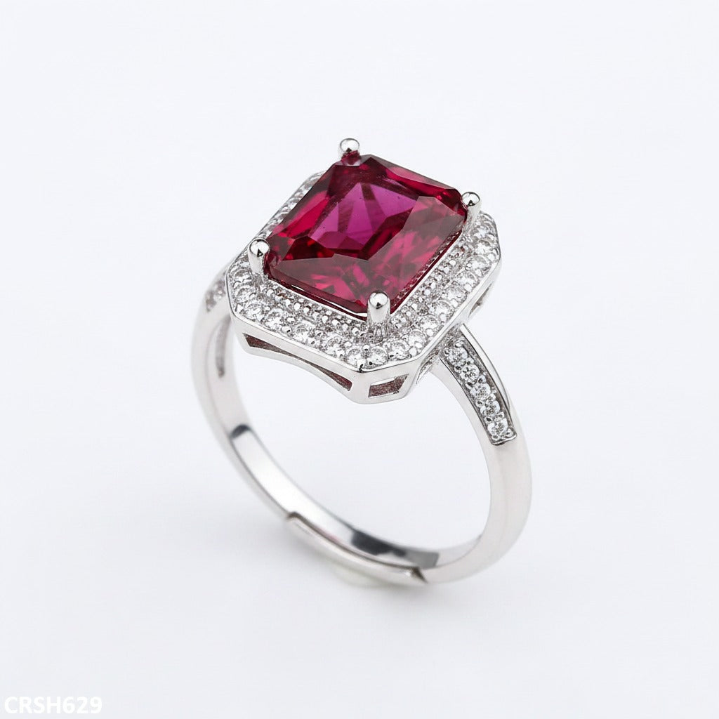 Silver ring with a red gemstone on a white background