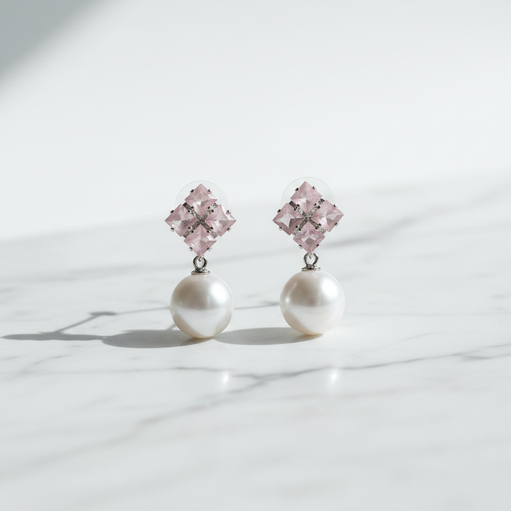 Pair of earrings with pink gemstones and pearl drops on a light background
